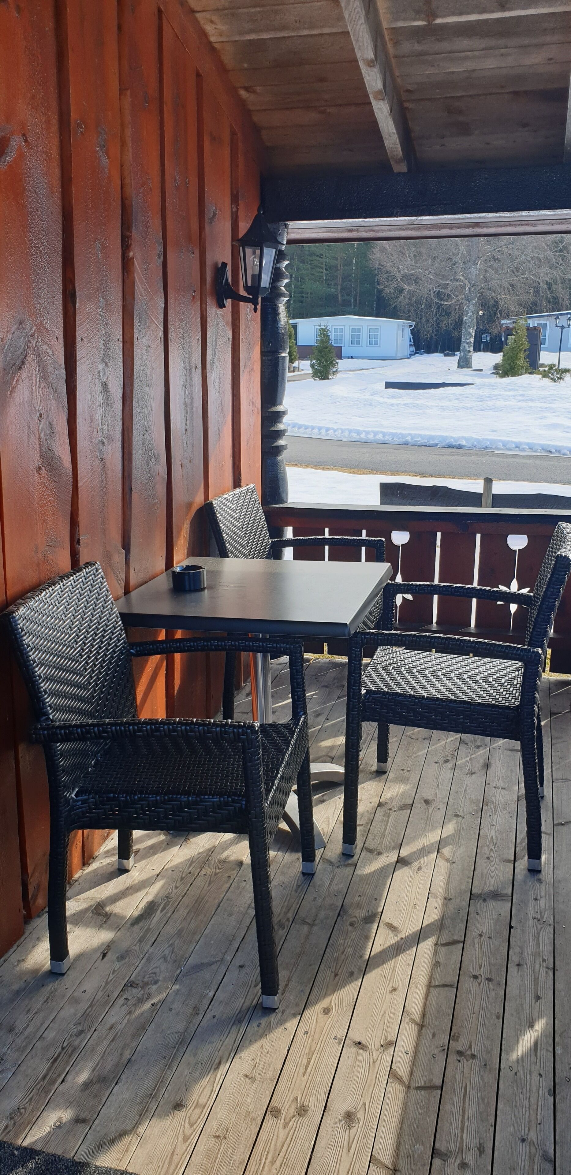 A wooden deck with a table and chairs, overlooking a snowy landscape.