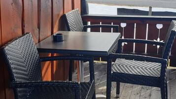 A wooden deck with a table and chairs, overlooking a snowy landscape.