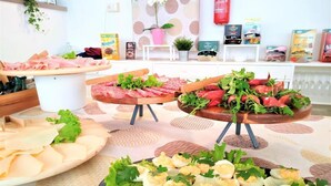 A buffet with various food items including sliced meats, egg salad, and fresh vegetables.