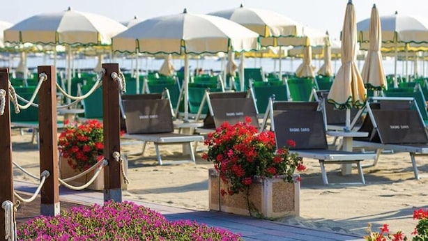 A beachside lounge area with sun umbrellas, lounge chairs, and flower planters.