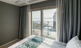 Habitación de hotel con cama, vista a un balcón y un amplio ventanal.