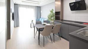 Una cocina moderna con horno empotrado, un comedor con mesa y sillas, y un televisor de pantalla plana en la pared.