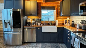 Una cocina moderna con electrodomésticos de acero inoxidable, armarios oscuros y techo de madera.