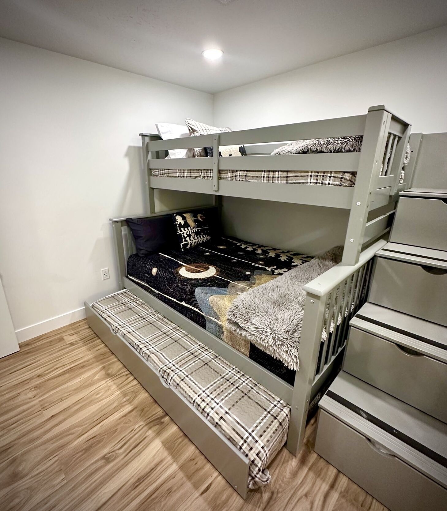 A bunk bed with a lower bunk and a desk attached to the side.