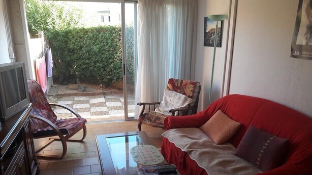 A cozy living room with a red sofa, a rocking chair, and a glass coffee table.