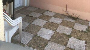 A small outdoor area with a checkered floor, a white door, and a clothesline with blue clothespins.
