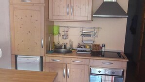 A compact kitchen with wooden cabinets, a built-in oven, and a stainless steel range hood.