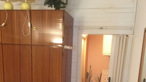 A bedroom with a bed, wooden wardrobe, and a bathroom visible through an open door.