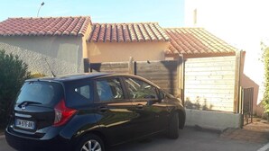 A black car parked in a driveway with a house in the background.