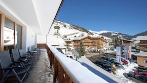 A balcony with a view of a snow-covered mountain and a building with a wooden facade. - Top Location Gerlos! - Lovely Apartment - 6P (Gerlos)