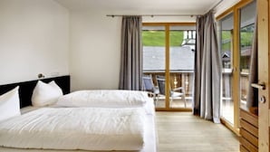 A hotel room with a bed, a wooden floor, and a balcony with a view of a house. - Top Location Gerlos! - Lovely Apartment - 6P (Gerlos)