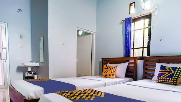A hotel room with two beds, a sink, and a window with curtains.