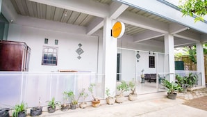 A covered outdoor area with a white building, a sign that says "SPOT ON", and several potted plants arranged along the edge.