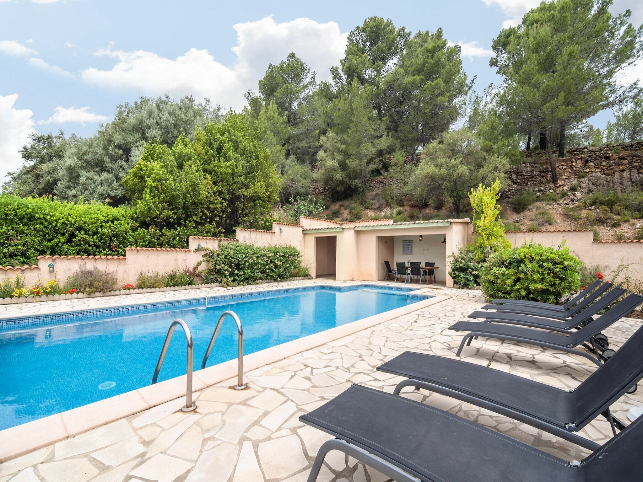 Una piscina amb gandules i una zona de seients coberta.