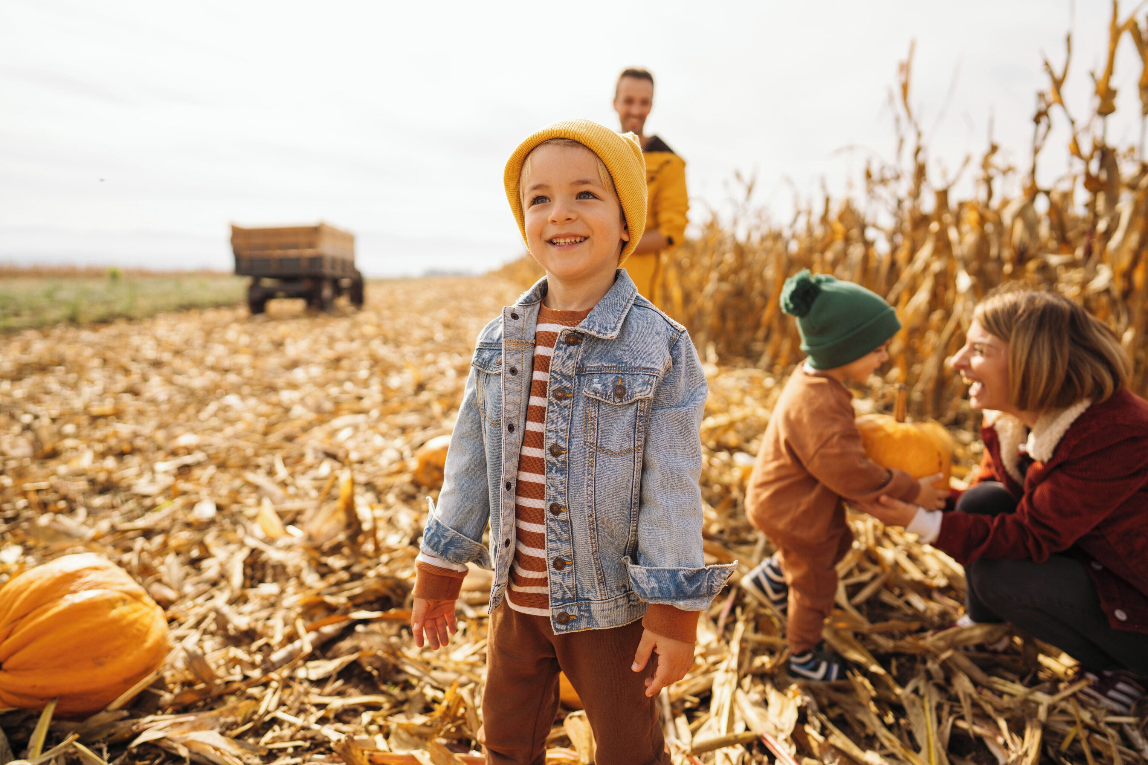 A child standing in a field with a tractor in the background.