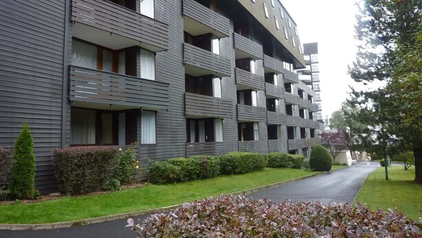 A multi-story residential building with balconies and a paved driveway.