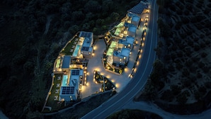 Vista aérea de un moderno complejo turístico con varias edificaciones, un camino sinuoso y paneles solares.