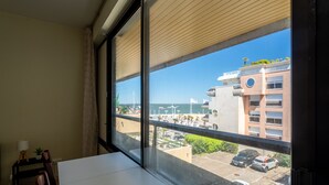 Una habitación con un ventanal grande que da a una vista de la ciudad, incluyendo un edificio con un elemento circular y un estacionamiento.