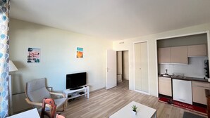 Un espacio habitable pequeño con televisión, zona de estar y kitchenette.