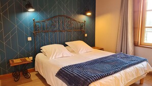A neatly made bed with a blue blanket, a metal headboard, and two bedside lamps.