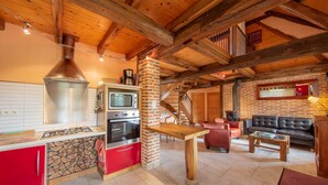 A rustic kitchen with a stone backsplash, a red cabinet, and a wooden table.