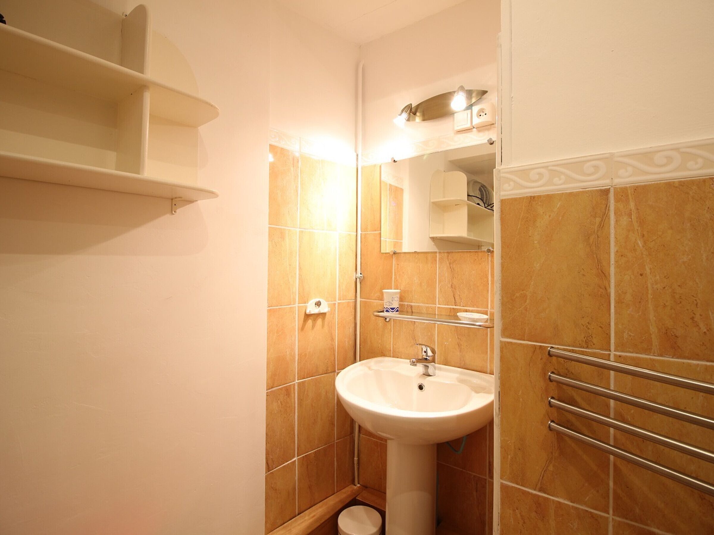 Une petite salle de bain avec un lavabo sur colonne, un porte-serviettes et une petite étagère.