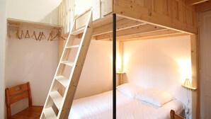 Habitación con literas de madera, una silla y una lámpara de noche.