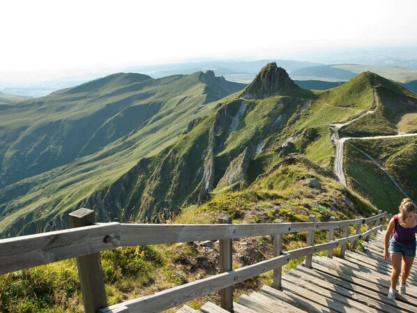 Eine Holztreppe führt einen Berg hinauf, mit Blick auf die umliegende Landschaft.