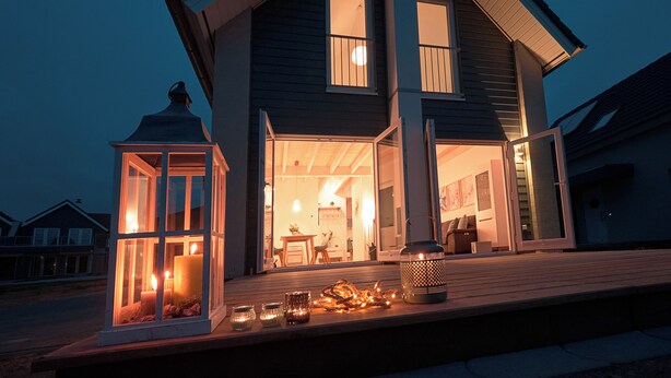 A two-story house with a large open porch, a lit candle, and a lantern. - Hyggehus - infrared sauna, terrace, fireplace, close to the beach and the North (Büsum)