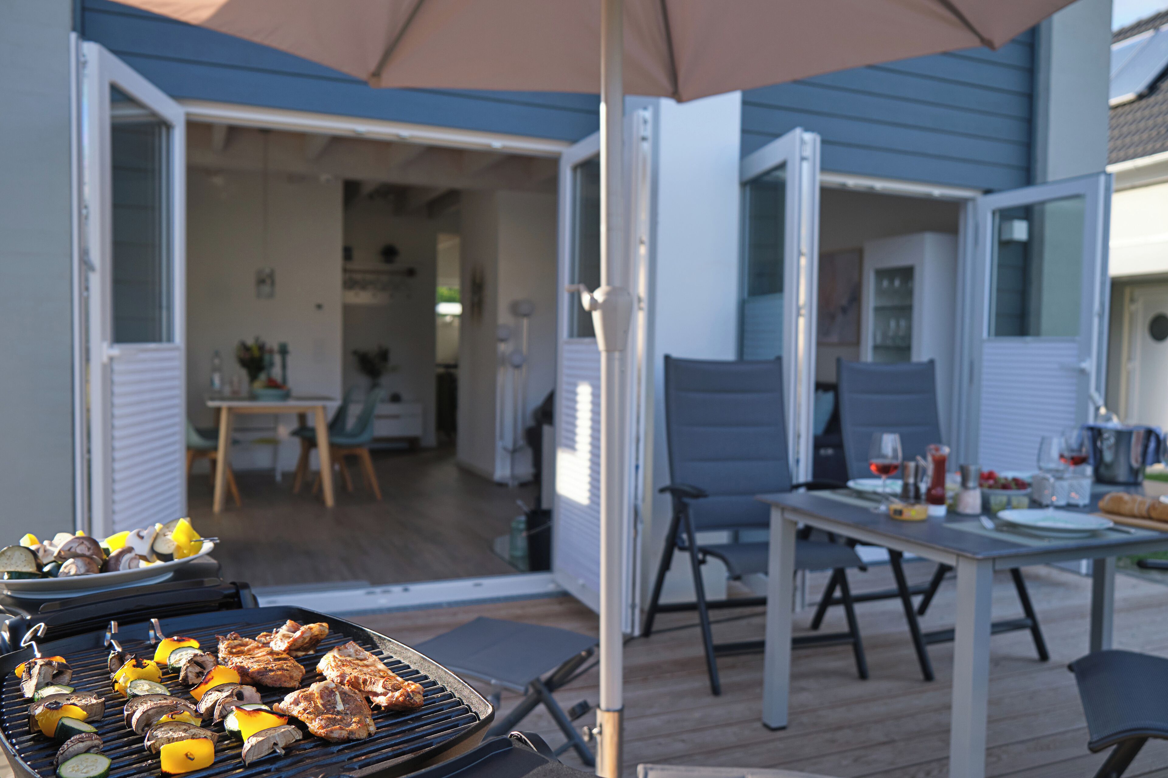 Un patio ouvert avec un barbecue, une table à manger et des chaises.