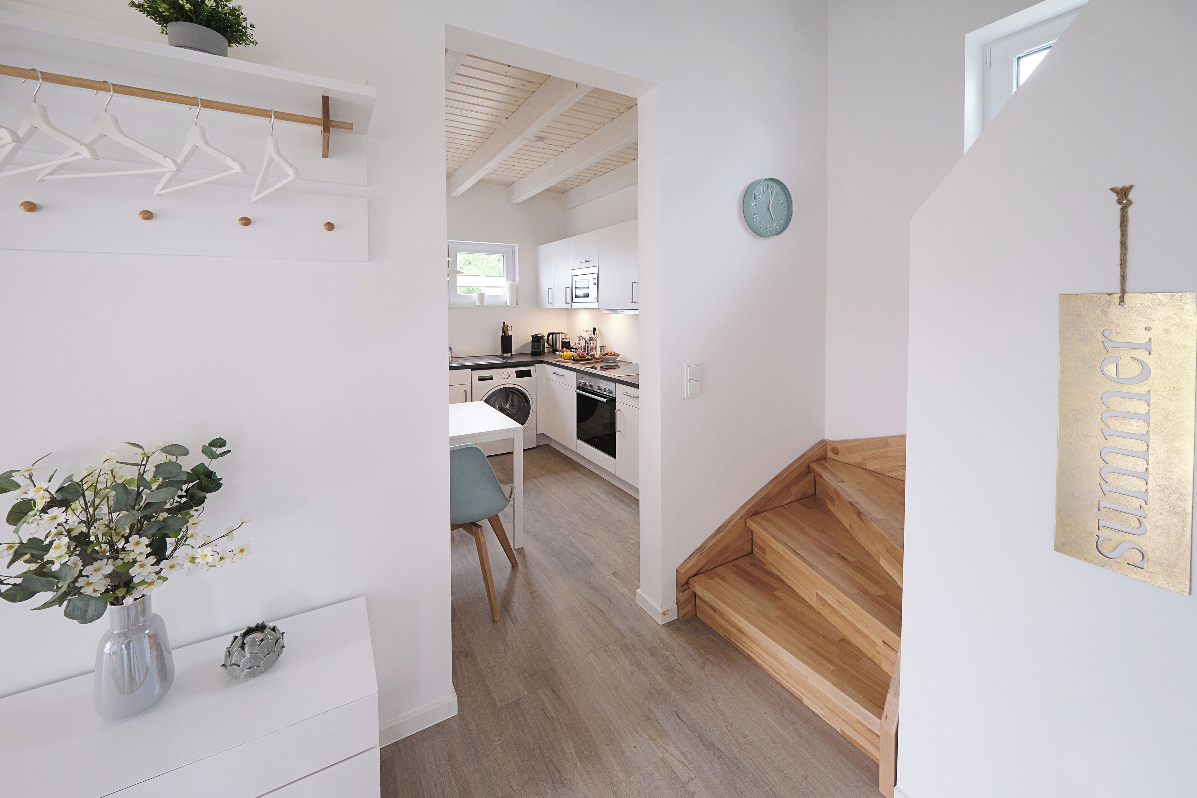 Eine moderne Küche mit weißen Schränken und einer Holztreppe.