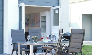 Un espace de restauration en plein air avec une table dressée pour deux personnes, entourée de chaises.