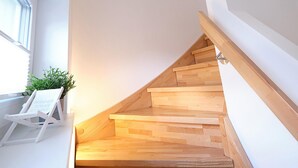 A wooden staircase with a white wall and a logo. - Hyggehus - infrared sauna, terrace, fireplace, close to the beach and the North (Büsum)