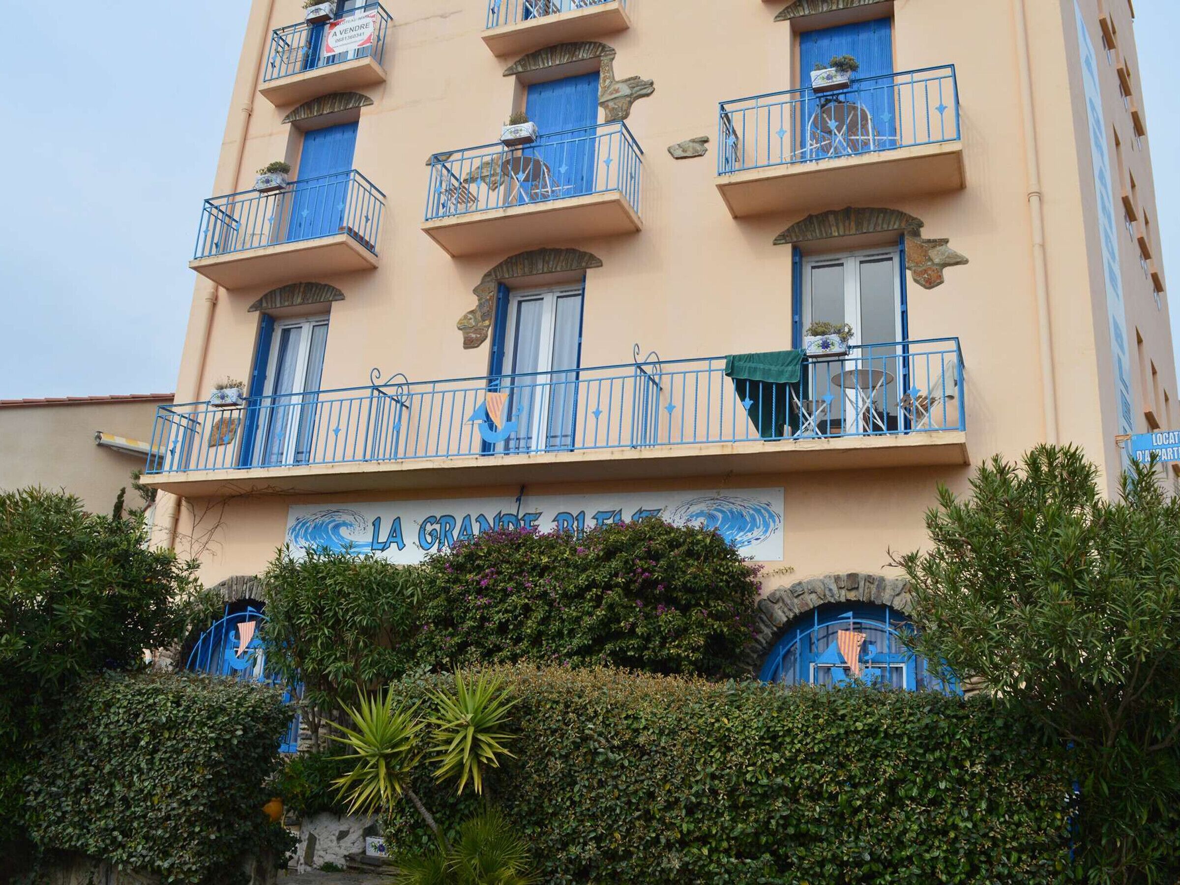 A multi-story building with balconies, some with plants and outdoor furniture.