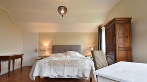 Ein Schlafzimmer mit einem großen Bett, Holzboden, einem Kleiderschrank und einem Tisch.