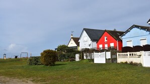 Eine Reihe farbenfroher Häuser mit einer grünen Wiese im Vordergrund und blauem Himmel.