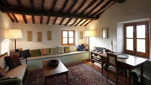 A cozy living room with a wooden ceiling, a sofa, a table, and a window. - CORZANELLO - Charming farmhouse in the Chianti with  swimming pool use (Calzaiolo)