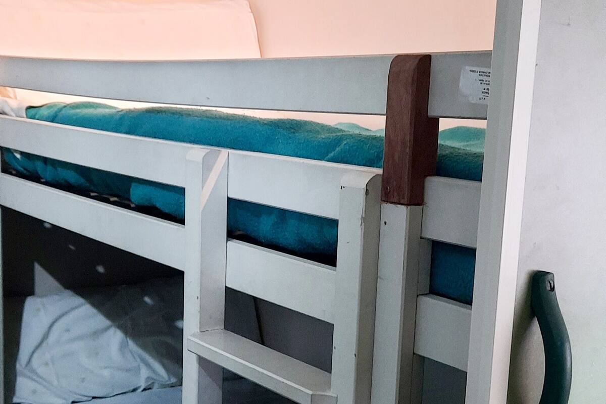 A bunk bed with a ladder, a white wall, and a wooden floor.