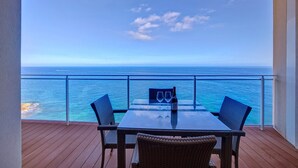 A balcony with a table and chairs overlooking the ocean. - Luxurious Apt With Ocean Views and Pool in Tigne Point (Sliema)