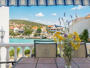 Enjoy a serene view of the coastal town from this terrace, featuring a table and chairs.