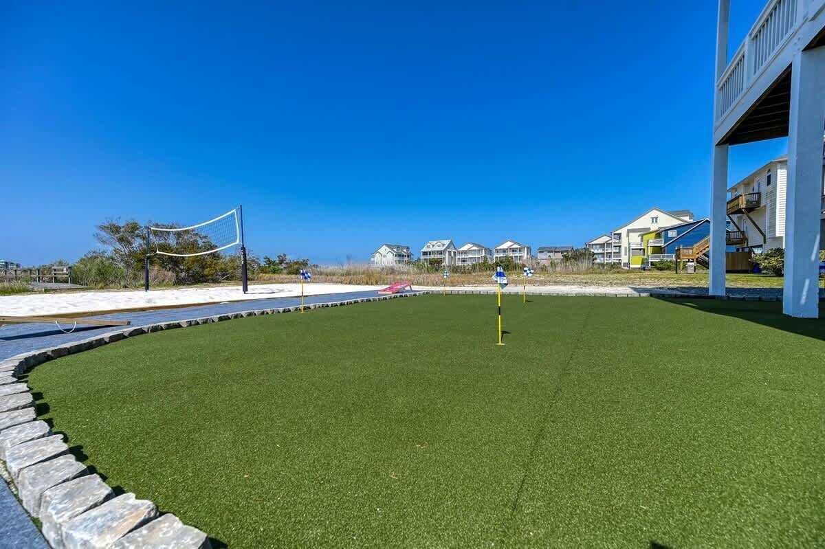 A well-maintained artificial turf sports court with a net, surrounded by a stone border.