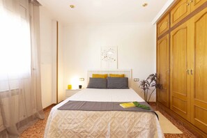 A bedroom with a bed, bedside table, lamp, and wardrobe.