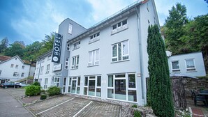 A hotel with a modern facade, large windows, and a paved driveway. - Taste Smart Hotel Backnang (Backnang)
