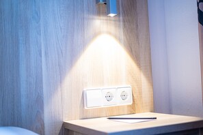 A wooden wall with a light fixture and three electrical outlets. - Taste Smart Hotel Backnang (Backnang)