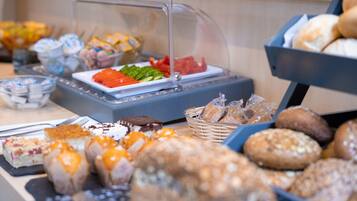 Ein reichhaltiges Buffet mit verschiedenen Speisen, darunter Gebäck, Obst und Desserts.