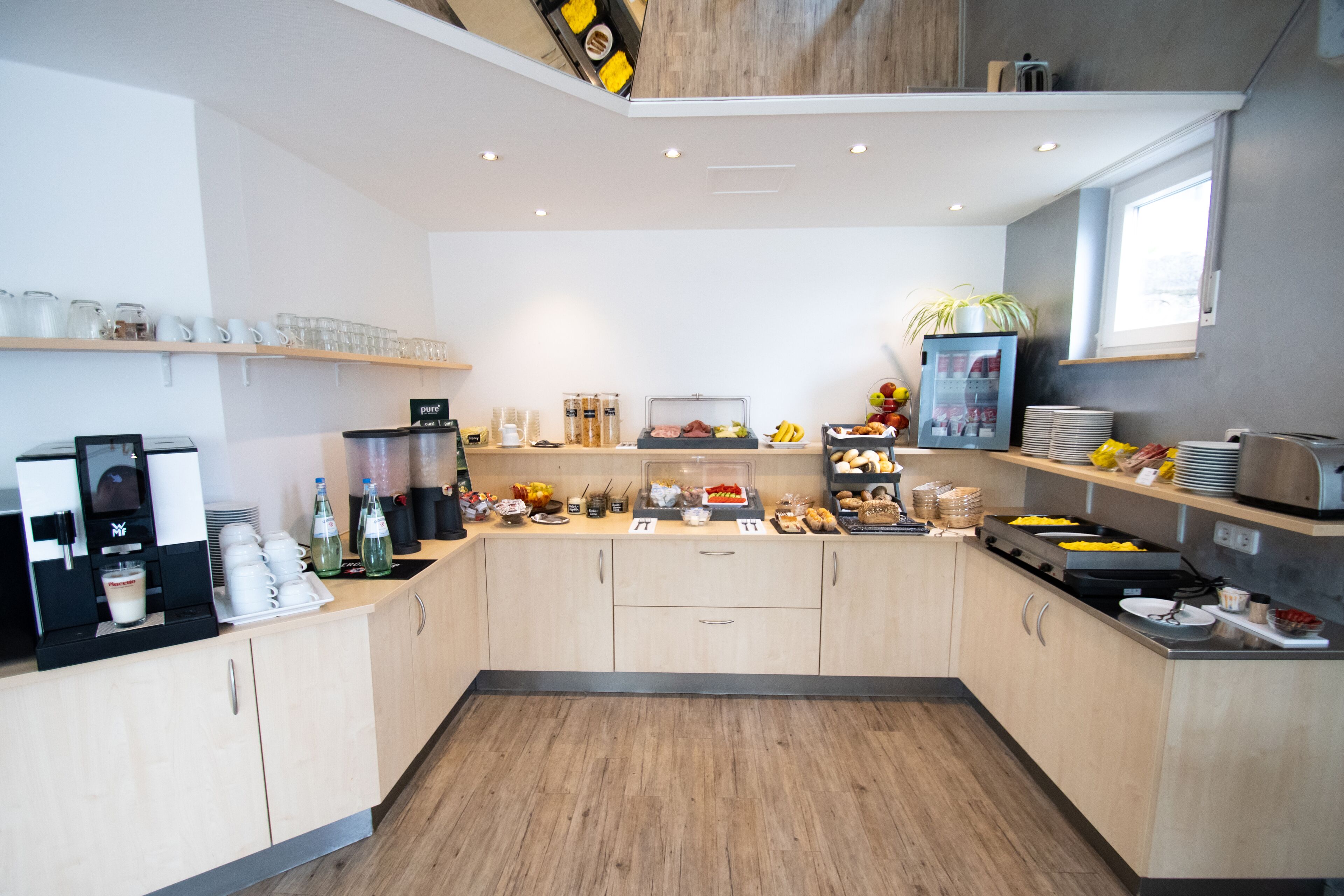 Una cocina moderna con estación de café, diferentes alimentos y un ventanal.