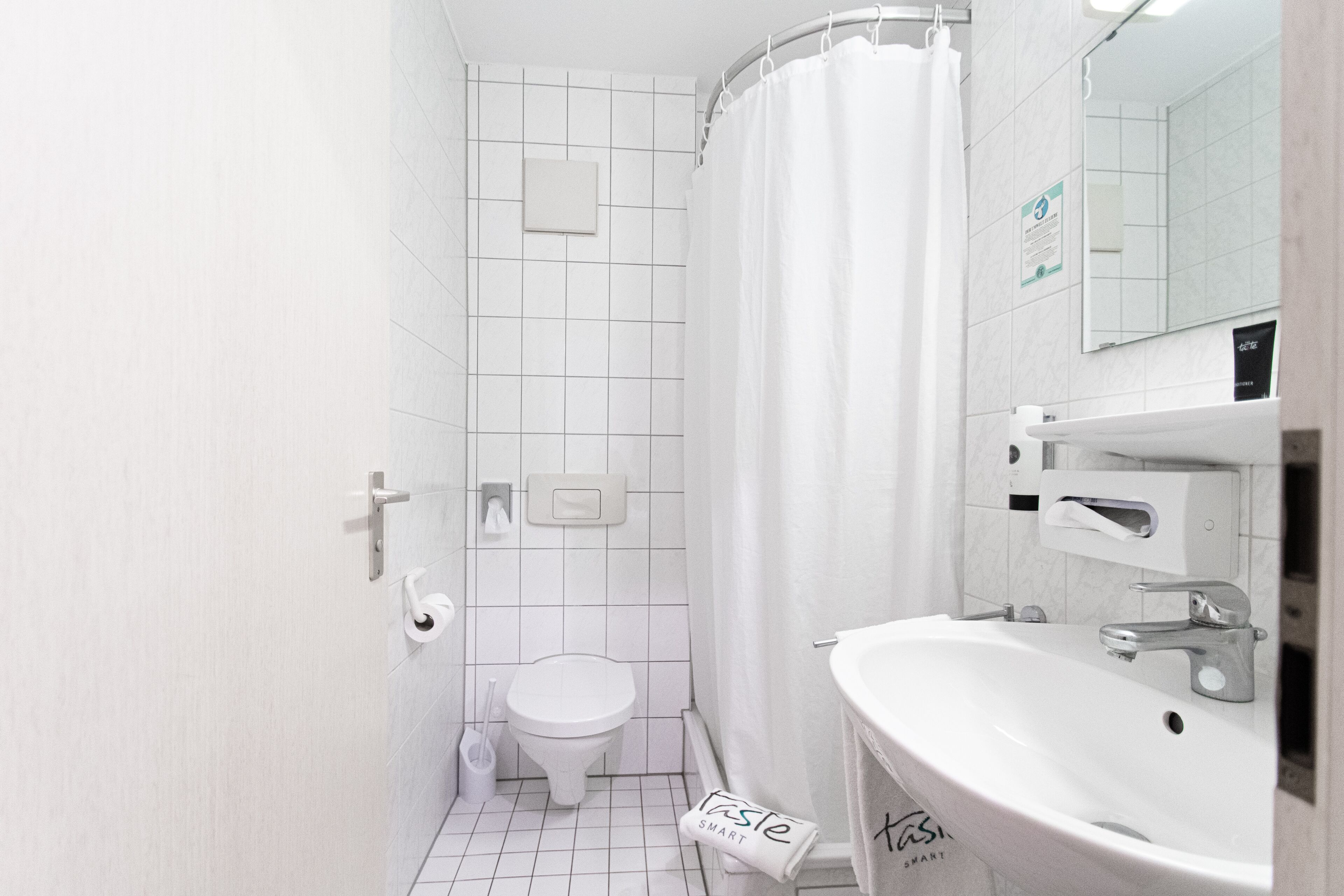 A small, modern bathroom with a toilet, a sink, and a shower curtain.