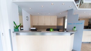 A modern kitchen with wooden cabinets, a stainless steel countertop, and a small potted plant. - Taste Smart Hotel Backnang (Backnang)