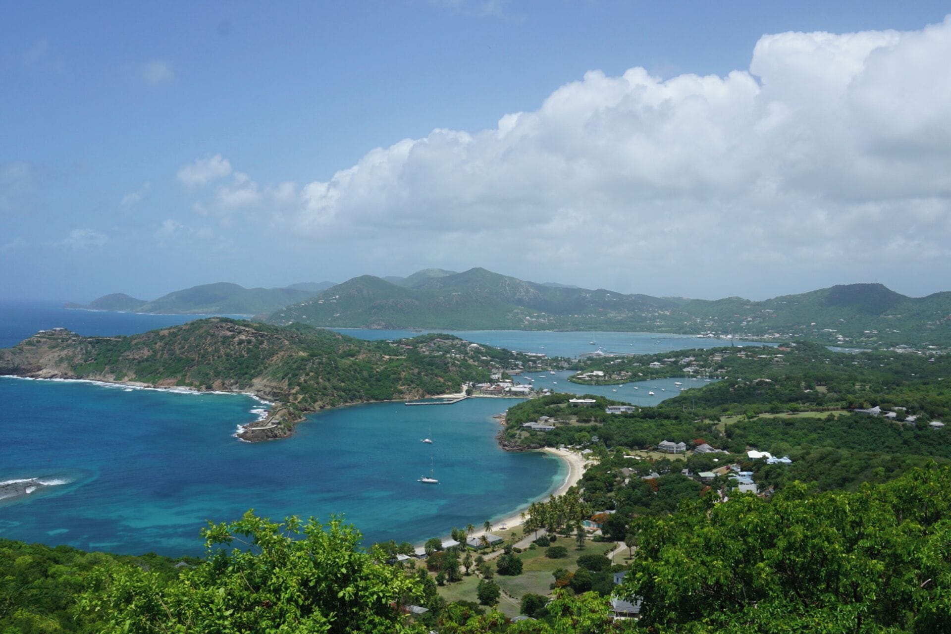 Un paysage côtier avec une baie, des eaux cristallines et des collines verdoyantes.