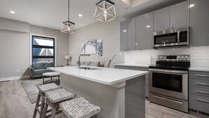 Una cocina moderna con una isla central, electrodomésticos de acero inoxidable e iluminación colgante.